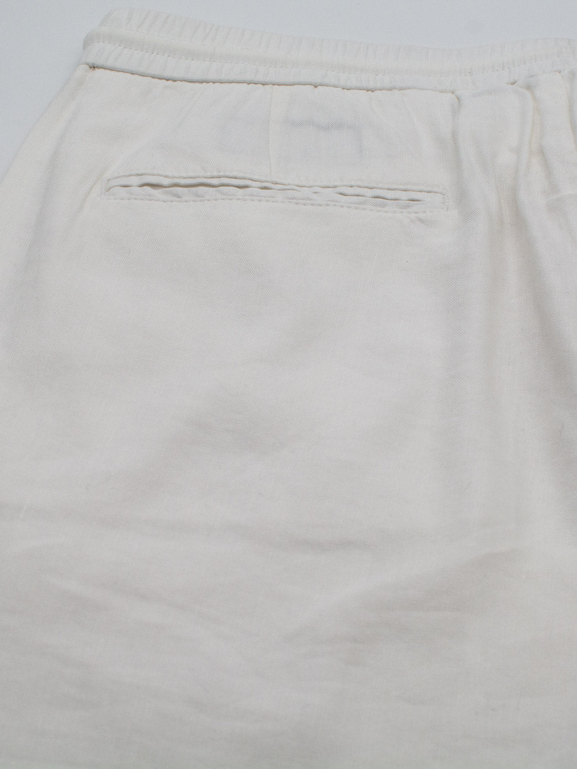 Close-up of the Bedford23 Linen Blend Drawstring Pant by ID Menswear, featuring a white garment with an elastic drawstring waistband and a single back pocket. The fabric is lightweight for ultimate comfort.