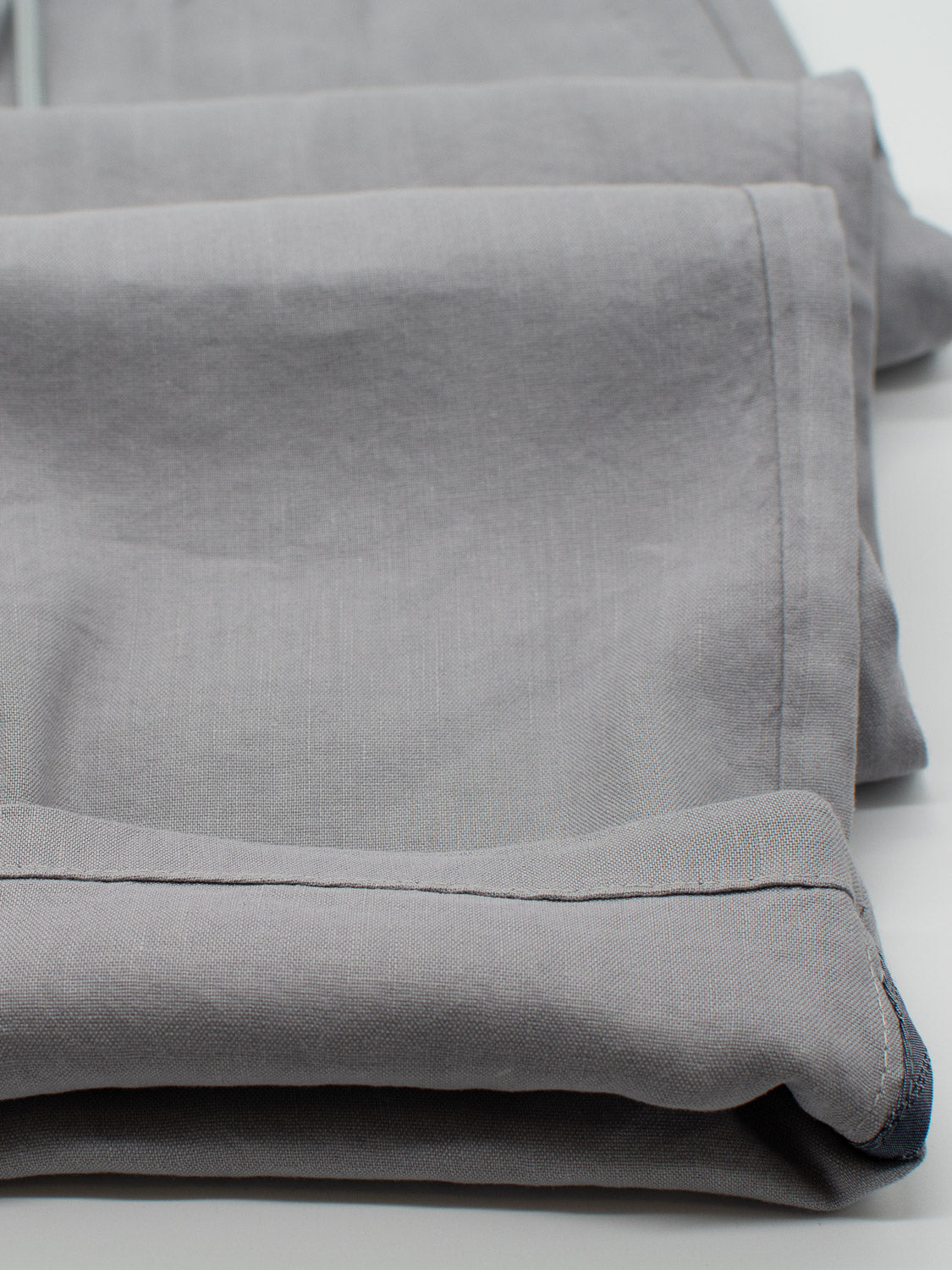 Folded Bedford23 Linen Blend Drawstring Pants by ID Menswear, featuring stitched hems and an elastic drawstring waistband, are neatly stacked on a white surface.