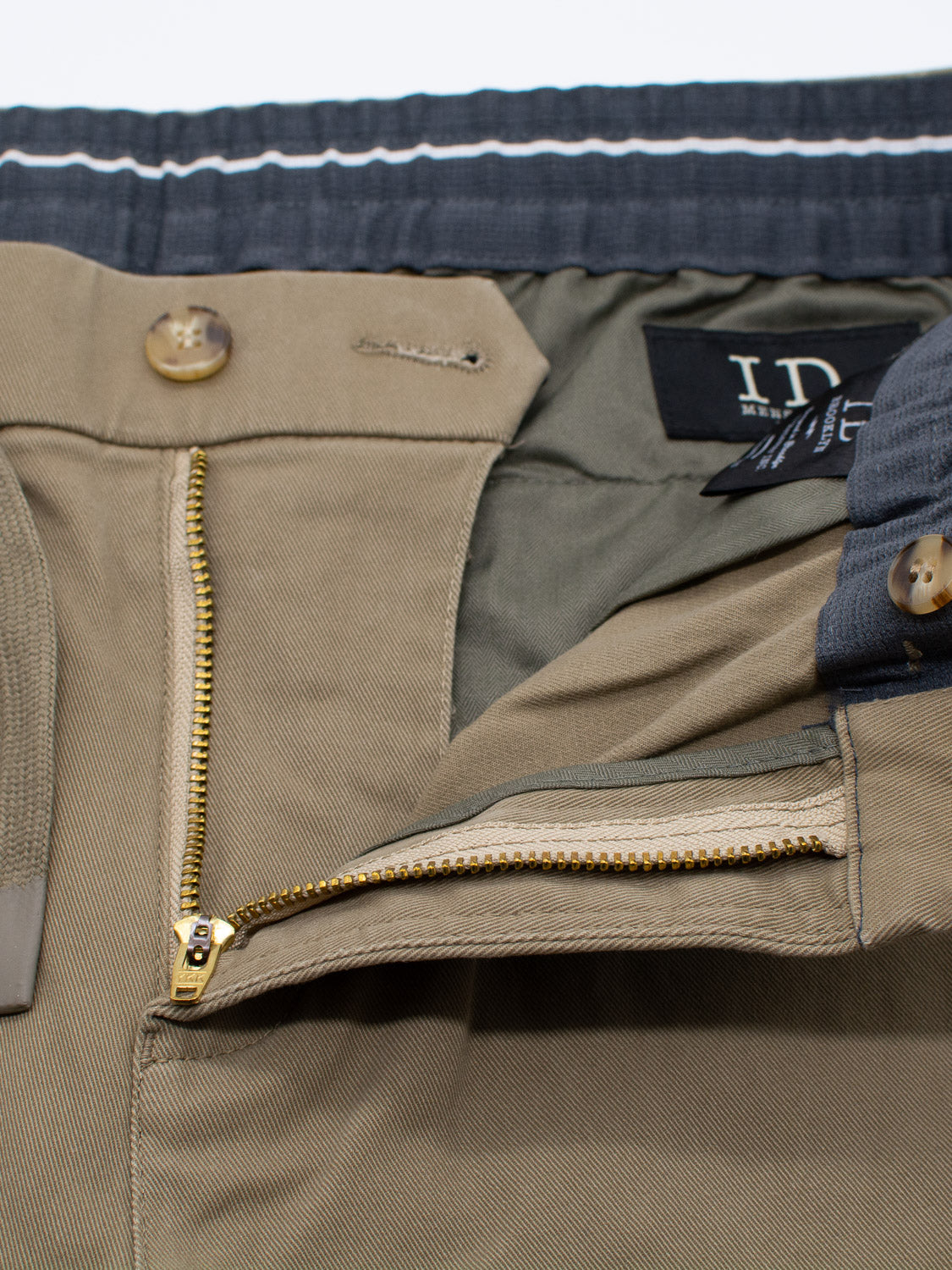 Close-up of the Dyker Cotton Twill Drawstring Jogger by ID Menswear showing a partially open fly with a brass zipper and button closure, two-button waistband with contrasting stitching, and a black label inside.