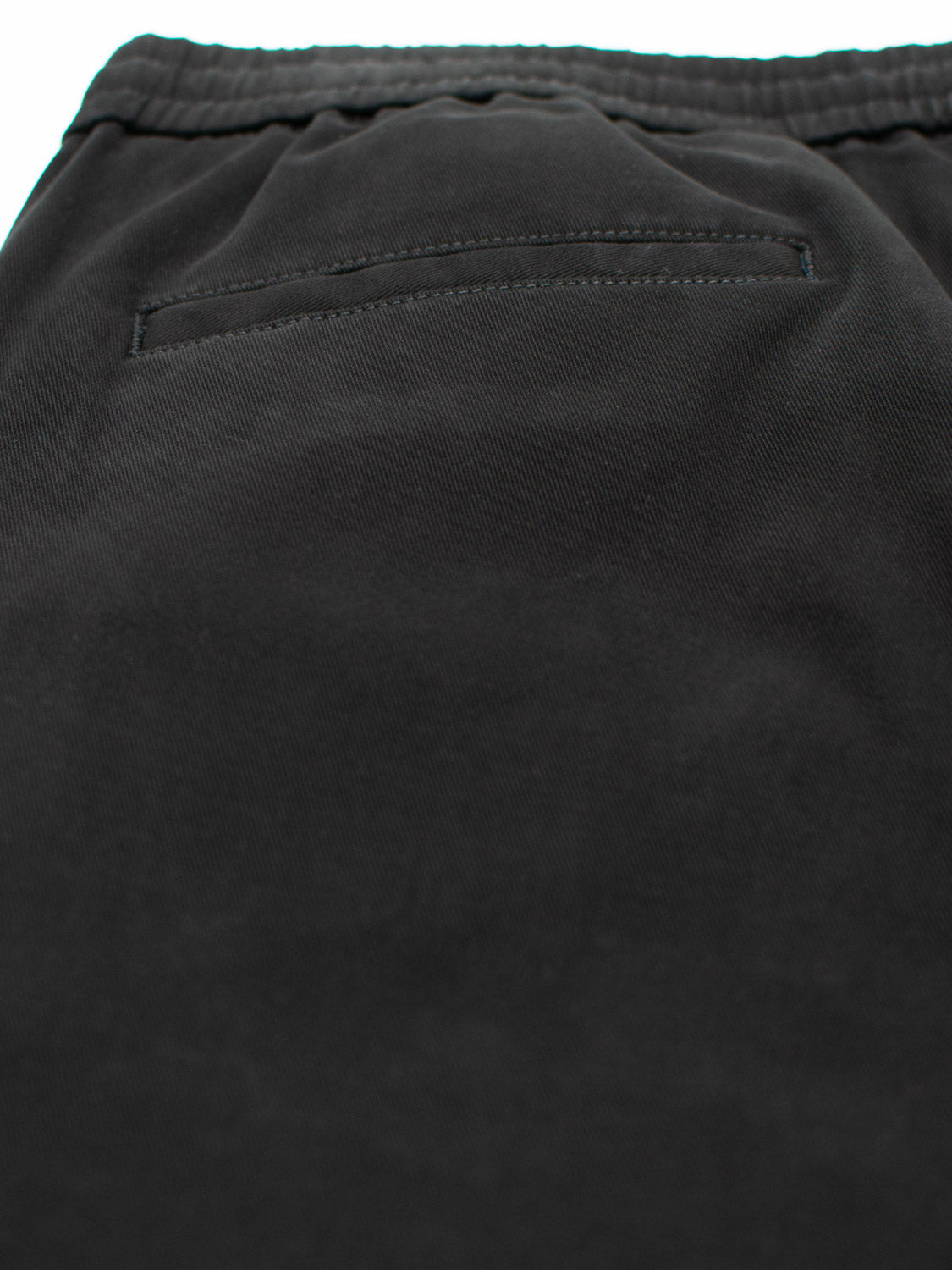 Close-up of the Dyker Cotton Twill Drawstring Jogger from ID Menswear in black. The smooth cotton twill features a single pocket stitched with precision, exuding a simple and minimalistic elegance.
