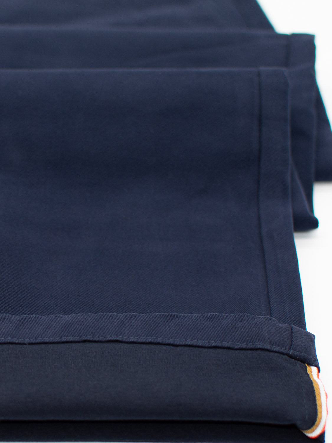 Close-up of neatly folded dark blue twill fabric with seams and edges visible, showcasing the smooth texture and layered precision reminiscent of Bushwick Twill Stretch Chino by ID Menswear.