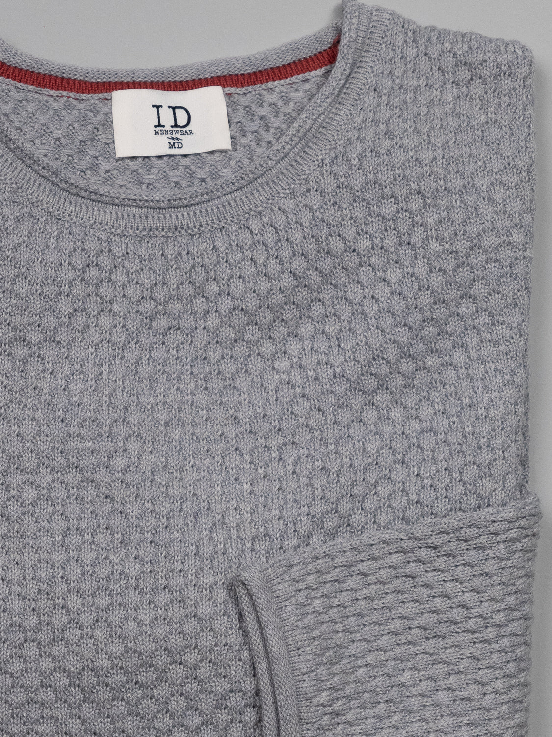 The Westside Rolled Neck Sweater from ID Menswear is a neatly folded textured gray piece, showcasing its waffle-knit pattern and red collar trim. The visible black ID label makes it ideal for casual knitwear enthusiasts.
