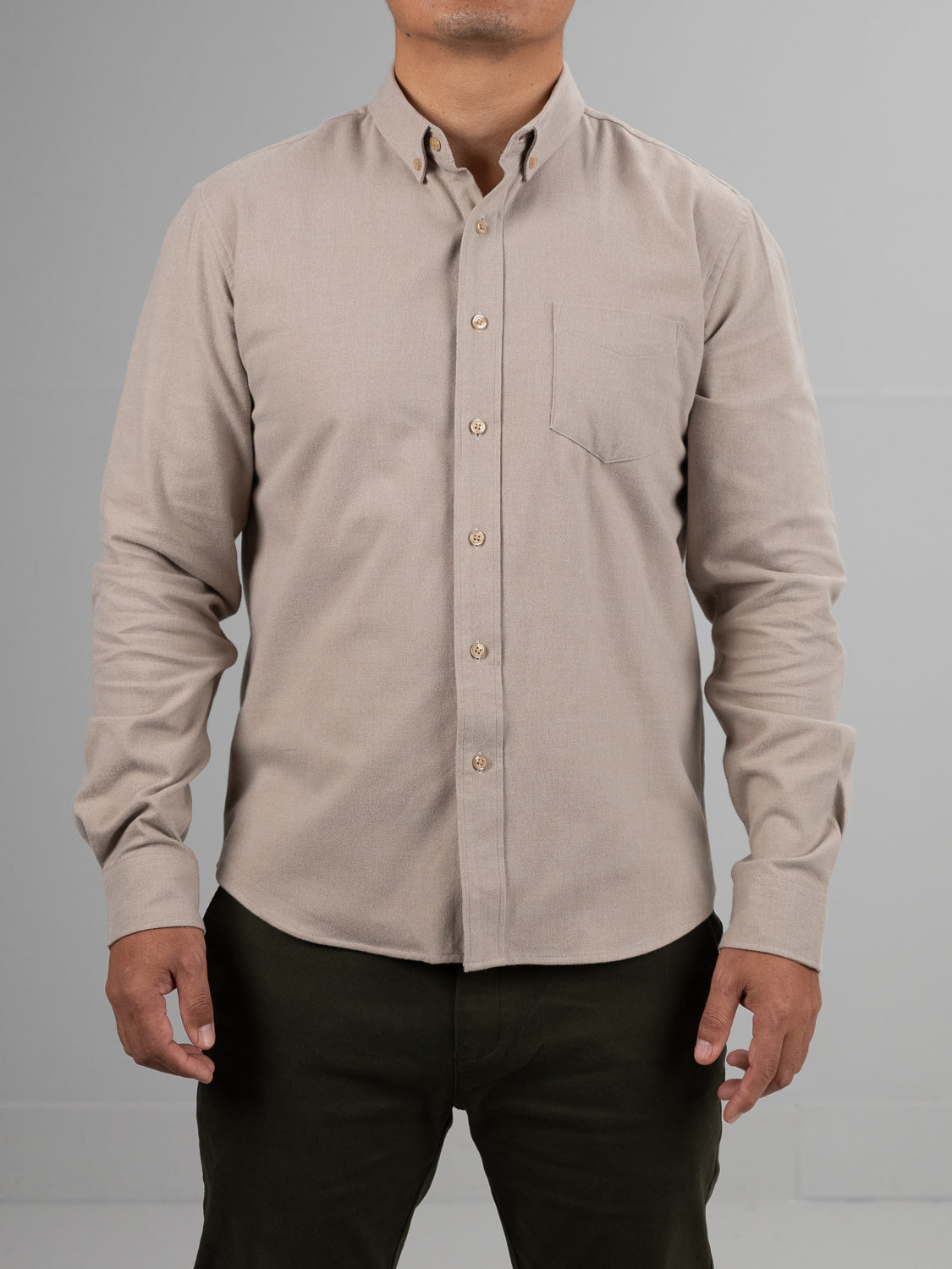 A person models the ID Menswear Rex Cotton Sustans Blends Flannel Shirt in beige, featuring a chest pocket, paired with dark green pants against a plain light gray background; their head is not visible.
