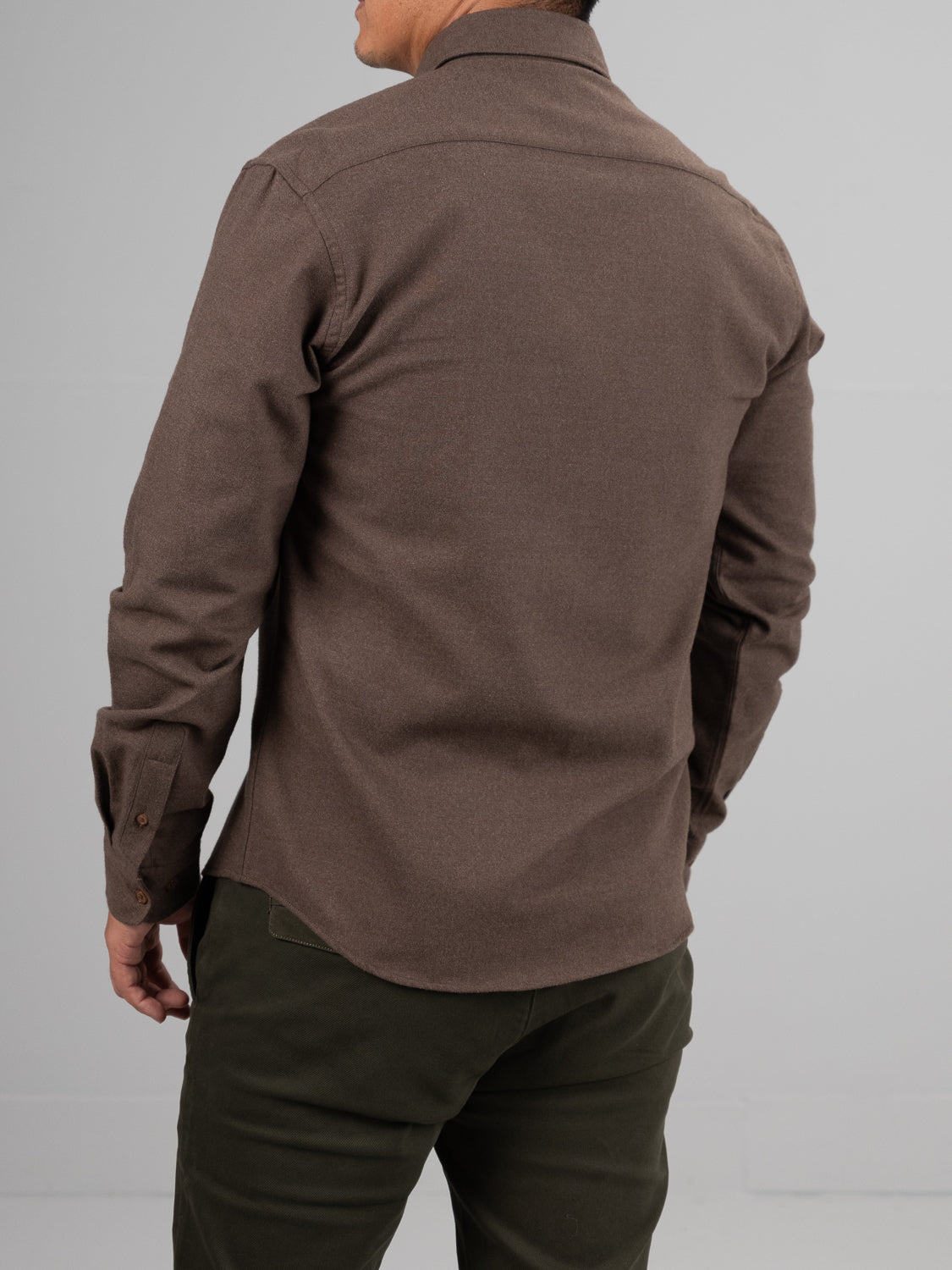 Seen from behind against a plain light gray background, a person wears the ID Menswear Rex Cotton Sustans Blends Flannel Shirt in brown and dark green pants.