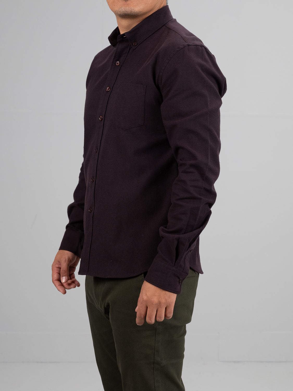 Someone is wearing the Magnus Brushed Twill Solid Flannel Shirt by ID Menswear with olive green pants, standing against a plain gray background. The photo captures them from the neck down and from the side, highlighting the textured charm of brushed twill fabric.