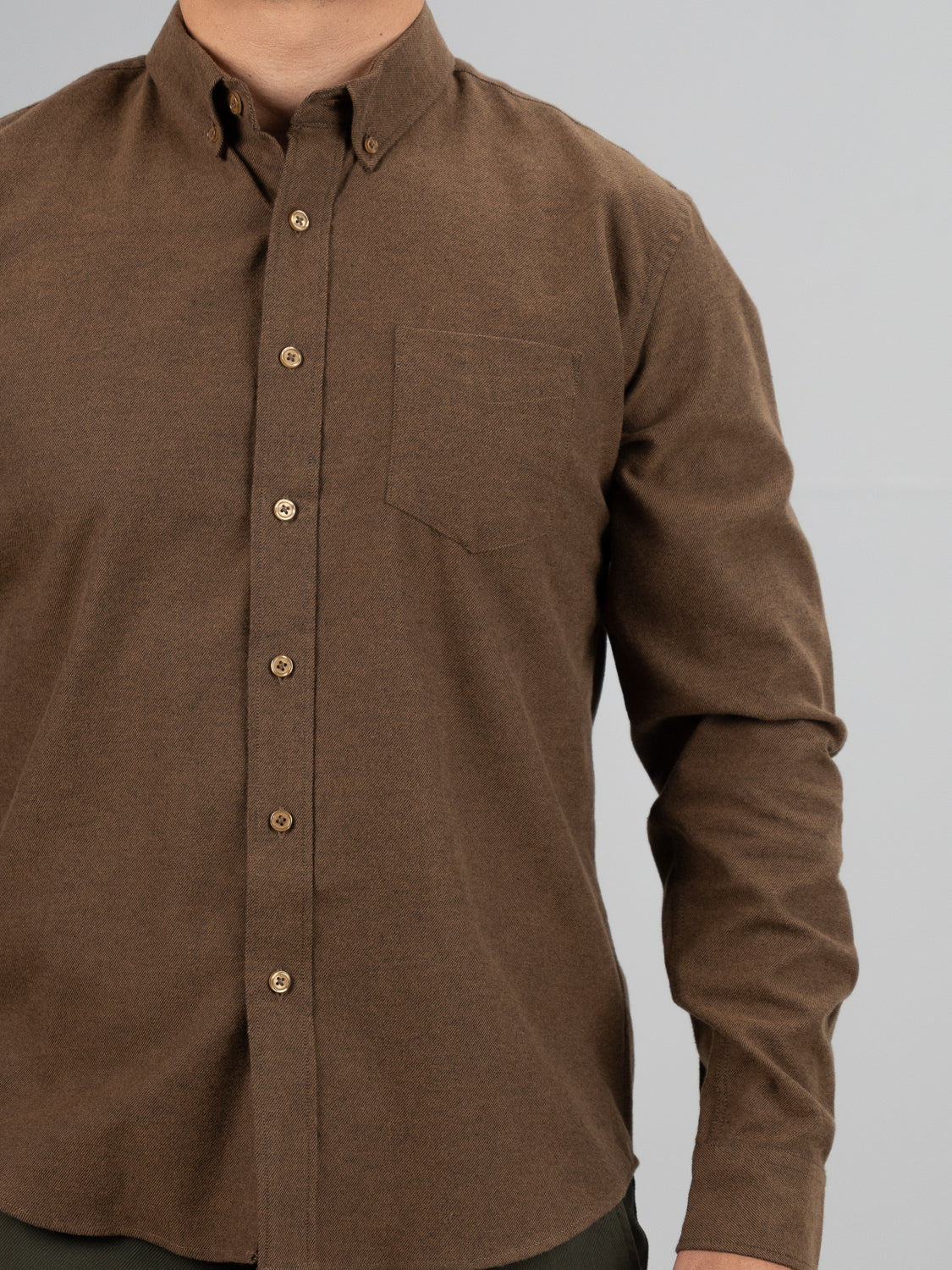 Someone wearing an ID Menswear Magnus Brushed Twill Solid Flannel Shirt, featuring a chest pocket and long sleeves, stands in front of a neutral background with their face not visible.