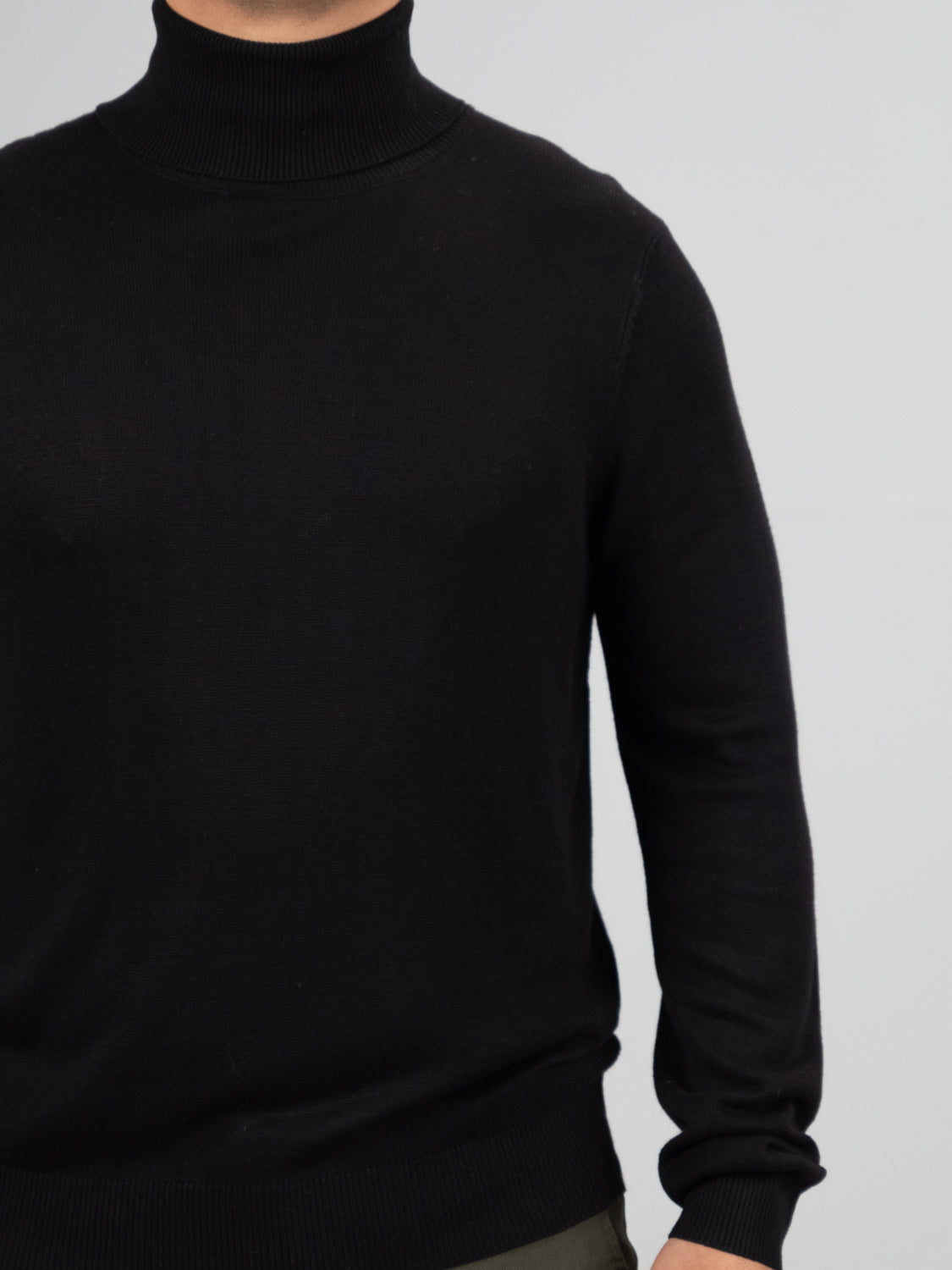 A person models an Oregon Viscose Turtle Neck by ID Menswear, cropped above the neck against a plain gray backdrop. Their left arm and part of their torso are visible. This soft and minimalist everyday piece blends comfort with style.