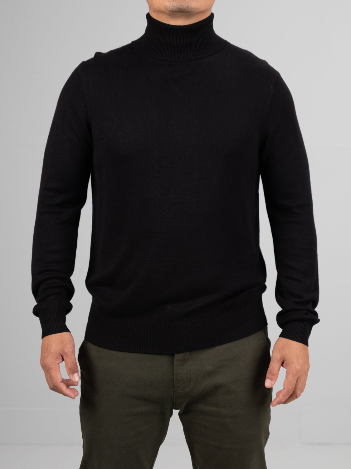 Against a plain gray backdrop, an individual dons the ID Menswear Oregon Viscose Turtle Neck and olive green pants. The face remains unseen. This soft, comfortable look embodies a simple, classic style ideal for daily wear.
