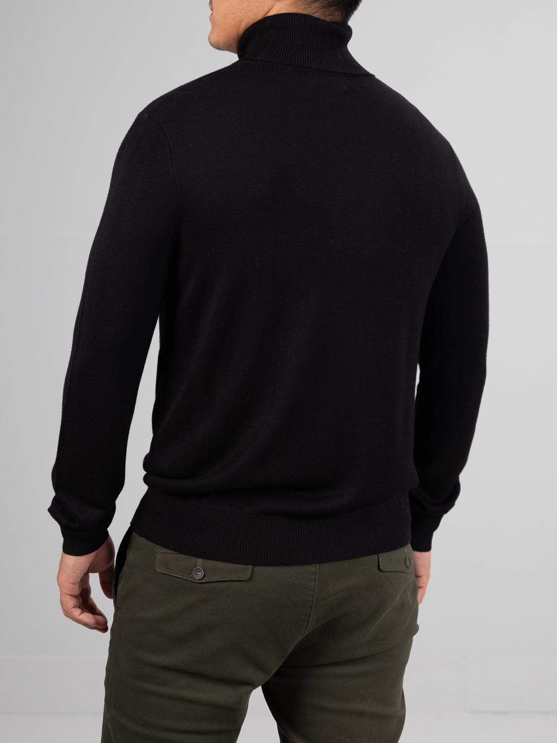 A person is viewed from behind wearing an Oregon Viscose Turtle Neck by ID Menswear, noted for its softness, paired with olive green pants against a plain background.