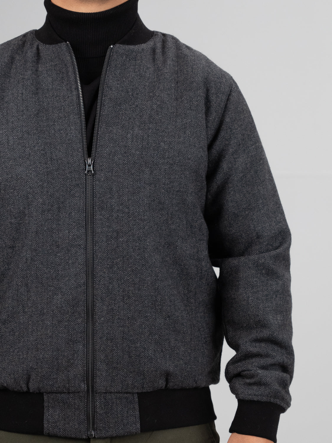 A person wears an ID Menswear Montauk Wool Blend Jacket in gray over a black top. The jacket features a front zipper, black ribbed collar, cuffs, and waistband. Only the upper body is visible against a plain light gray background.