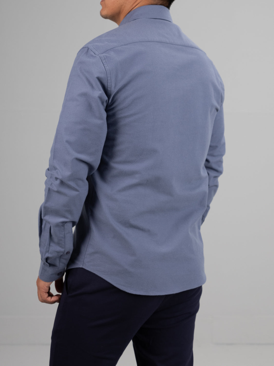 Someone in a Milo Brushed Oxford Flannel Cotton Shirt by ID Menswear and dark pants stands neutrally against a plain background, facing away.