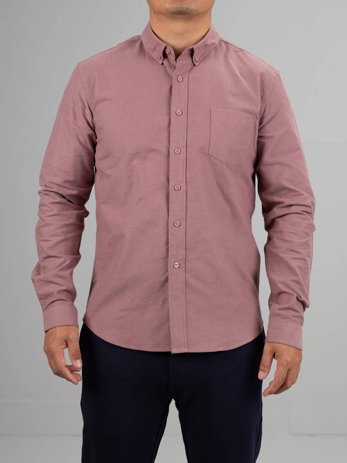 A person wearing the pink Milo Brushed Oxford Flannel Cotton Shirt from ID Menswear and dark pants stands against a plain gray background. The shirt boasts a pointed collar and chest pocket, with only the body visible in the image.