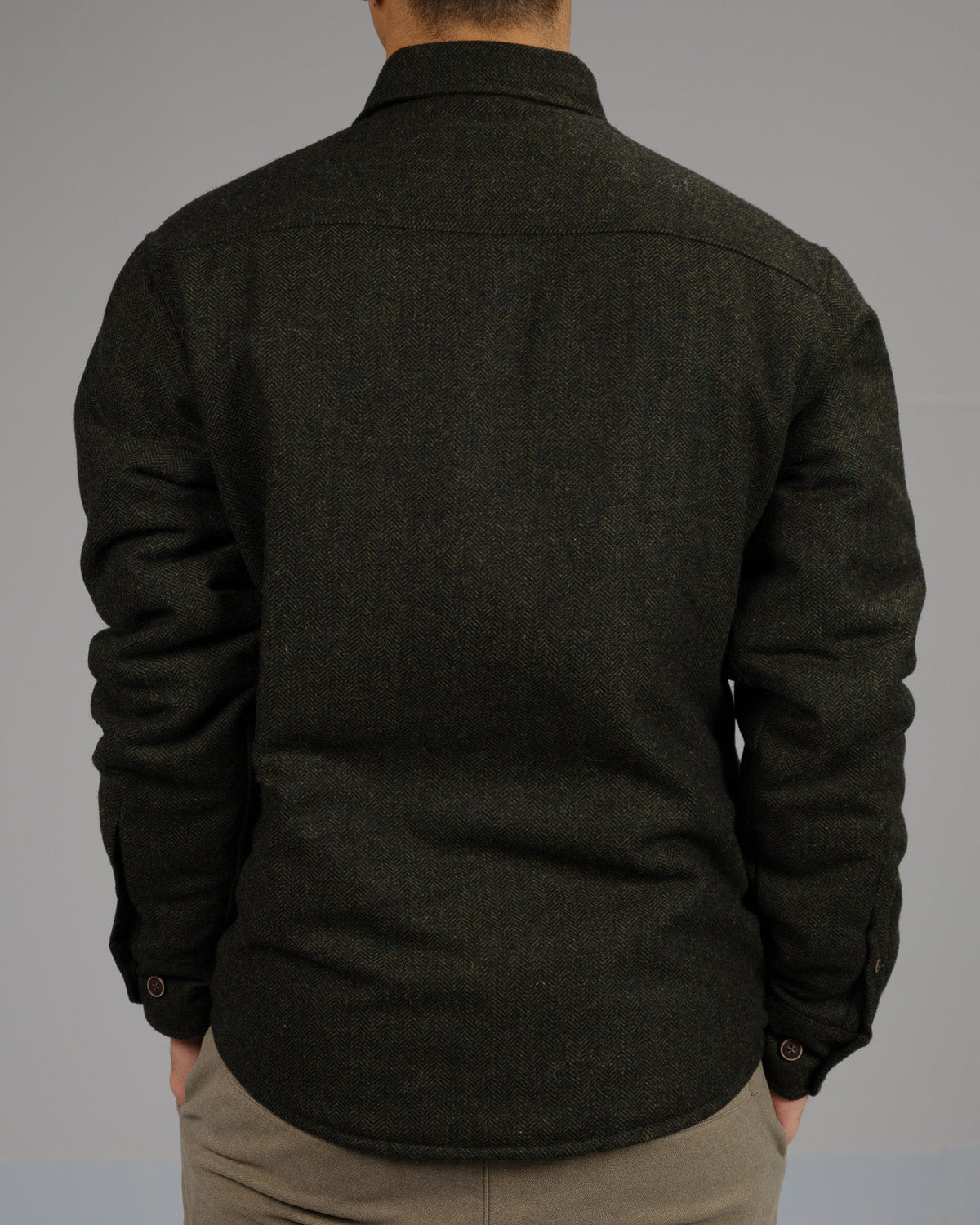 A person stands with their back to the camera, wearing the Stuntman Wool Blend Tweed Jacket by ID Menswear with light pants, set against a plain gray background.