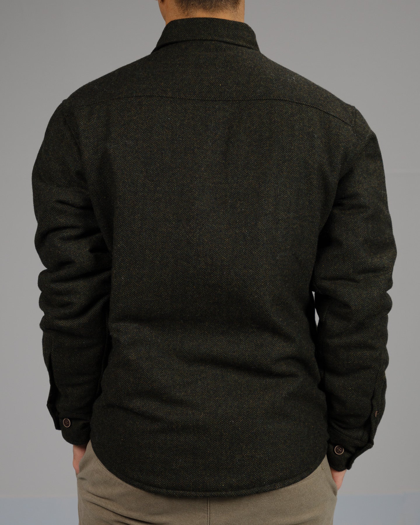 A person stands with their back to the camera, wearing the Stuntman Wool Blend Tweed Jacket by ID Menswear with light pants, set against a plain gray background.