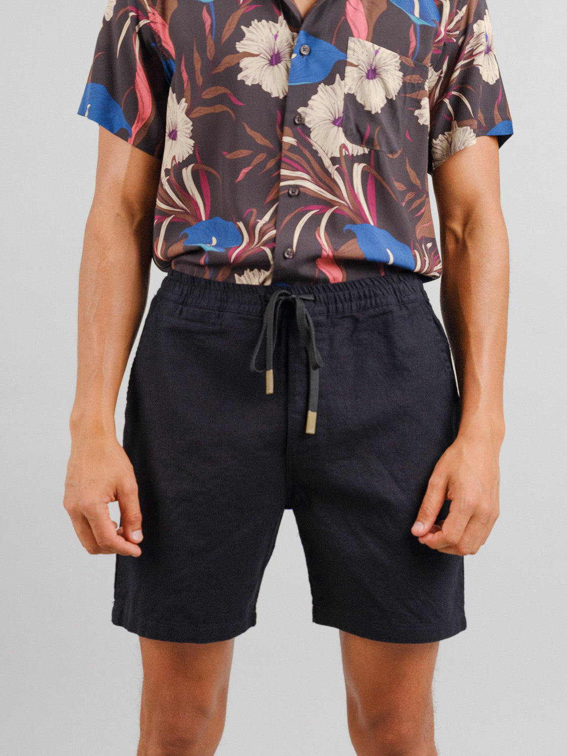 A person in a floral short-sleeve button-up shirt and ID Menswears Kotao Linen Blend Drawstring Shorts stands against a plain background, hands at sides.