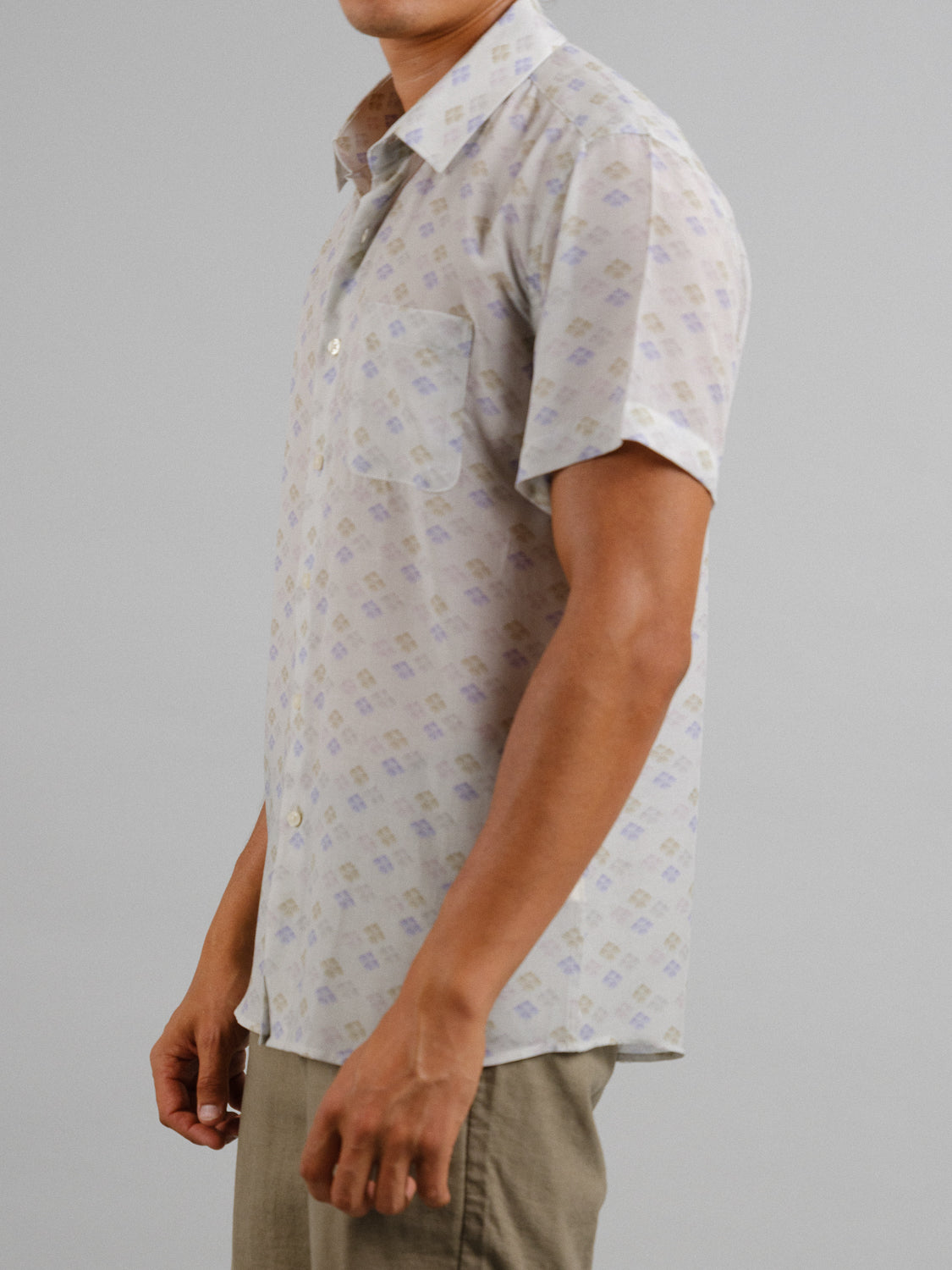 A person models the ID Menswear Hanabi Printed Tencel Linen Shirt, showcasing a light and subtly geometric-patterned short-sleeve design paired with khaki pants against a plain gray background, ideal for summer comfort.
