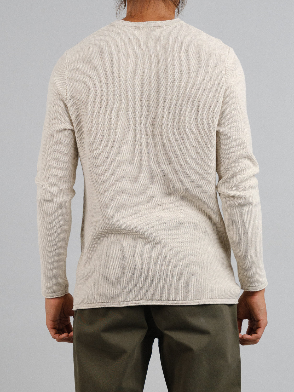 A person wearing the Madrid Rolled Neck Sweater Tee by ID Menswear, paired with olive-green pants, stands with their back to the camera against a plain gray background.