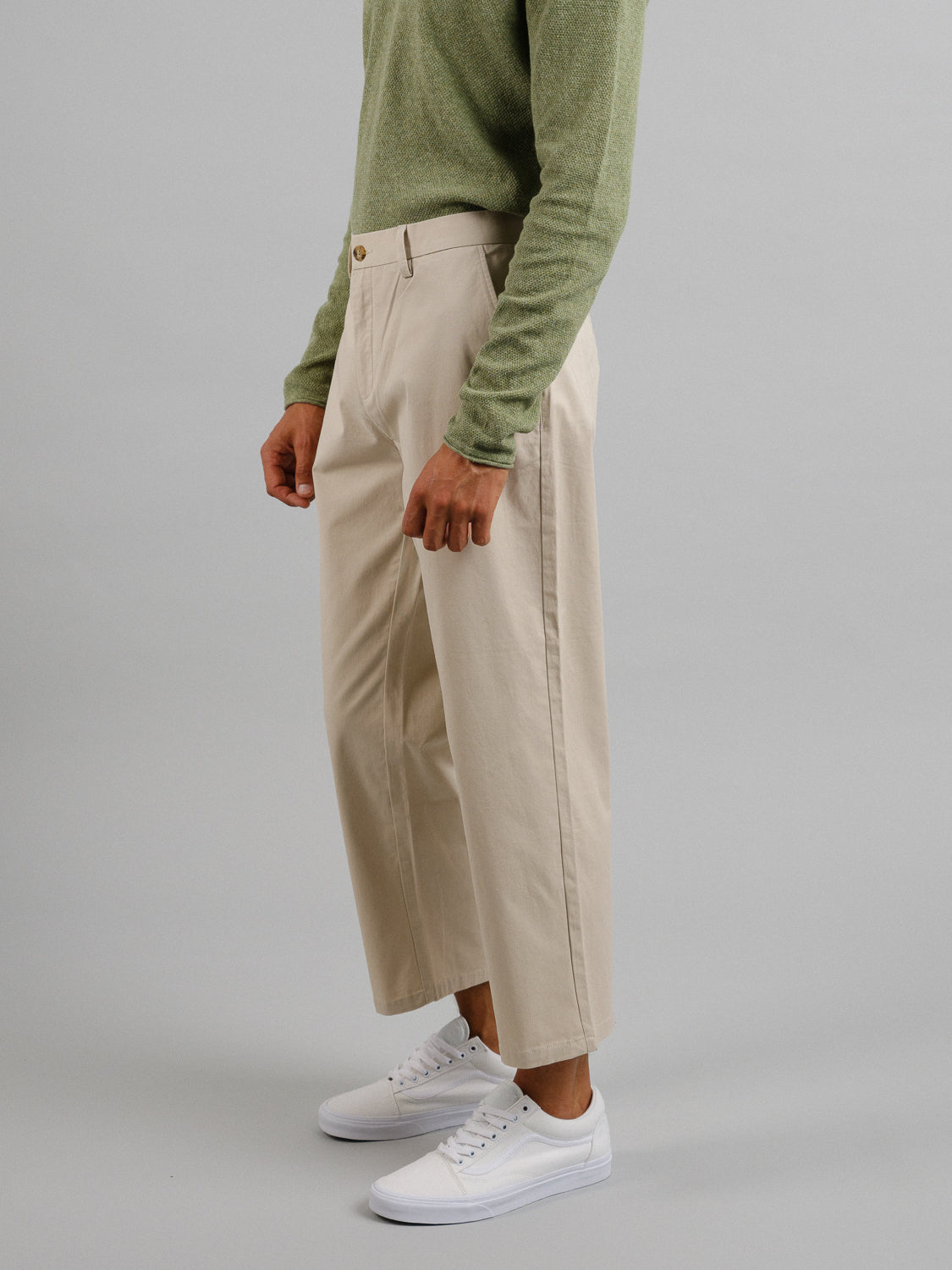 A person in a green sweater and ID Menswear’s Bigboy Relaxed Flooded Chino stands sideways, highlighting the relaxed, baggy fit with white sneakers against a plain backdrop.