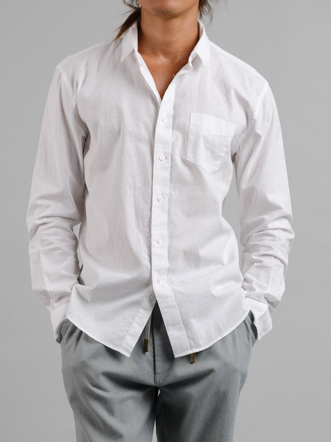 A person in a breathable ID Menswear Goa Linen Cotton Long Sleeve Shirt and gray pants stands against a plain gray background, hands casually tucked in pockets. Face is not visible.