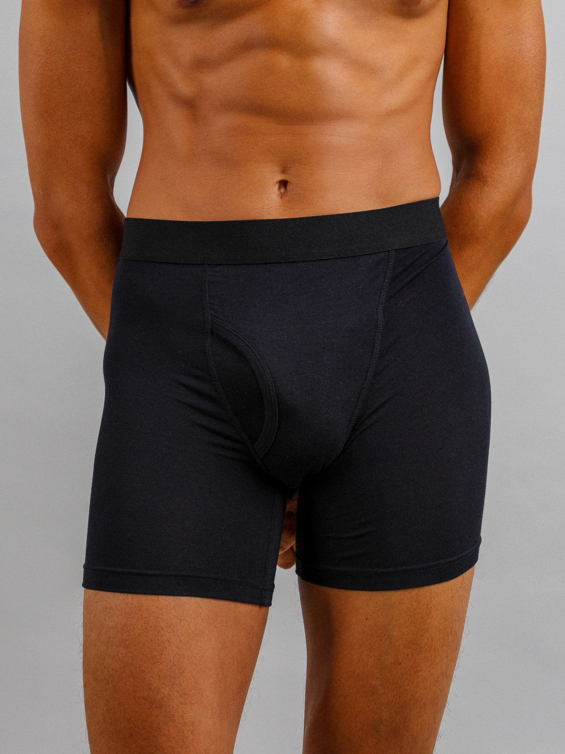 A model dons ID Modal Boxer Briefs by ID Menswear, posed against gray to display the fit and stretch. The midsection focus highlights the textured fabric and everyday comfort with hands relaxed at their sides.