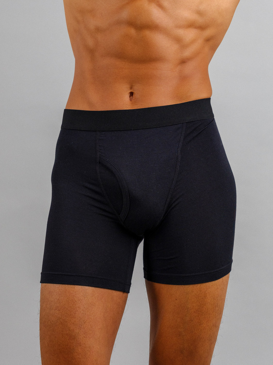 A person wears black ID Modal Boxer Briefs by ID Menswear against a gray background, shown mid-torso to thighs. The fitted waistband and seamless fabric deliver everyday comfort and stretch effortlessly for a perfect fit.
