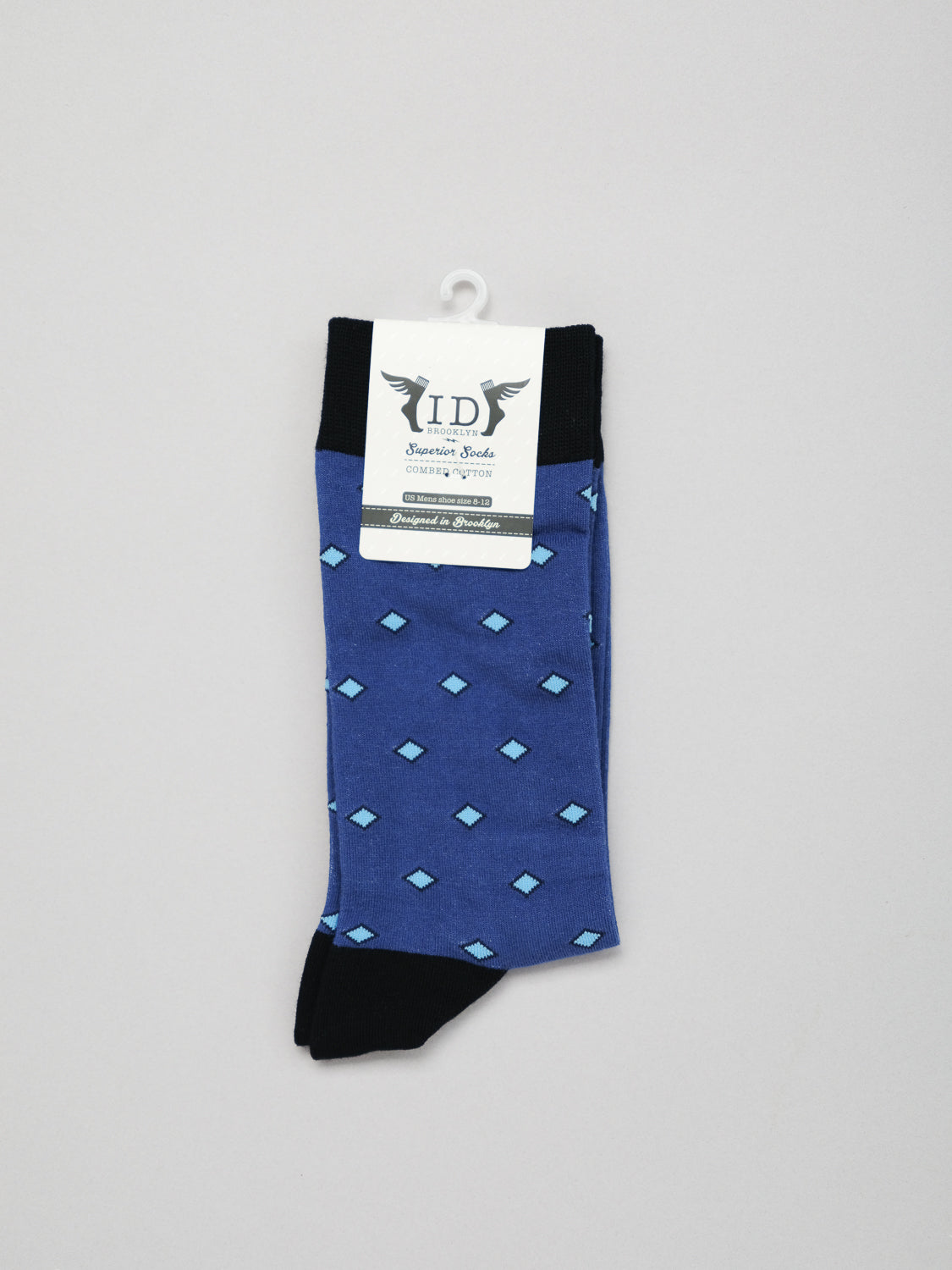 The Hishi Graphic Socks by ID Menswear feature a classic Japanese design with a light blue diamond pattern on blue fabric, complemented by black cuffs, heels, and toes. Made from soft combed cotton, the label reads Authentic Goods set in decorative lettering on a plain gray backdrop.