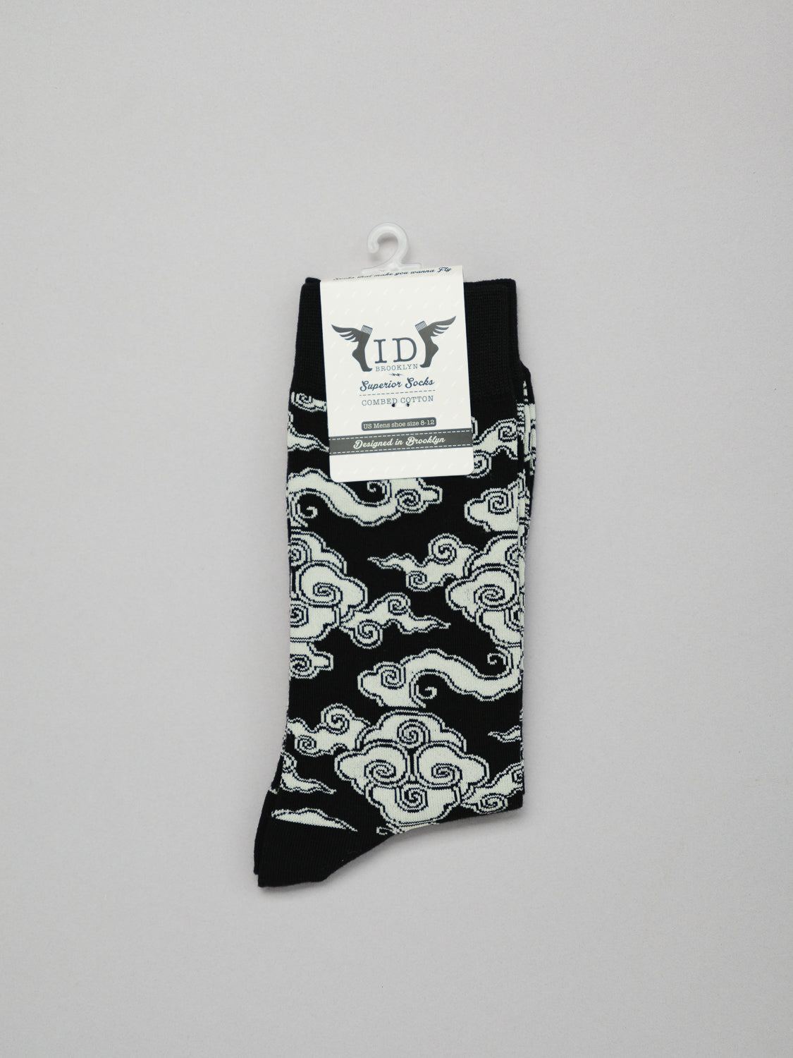 A pair of Cloud Graphic Socks from ID Menswear, featuring a black and white swirling cloud pattern on stretchy combed cotton, breathable and neatly folded. Displayed on a light gray background, they combine comfort with style.