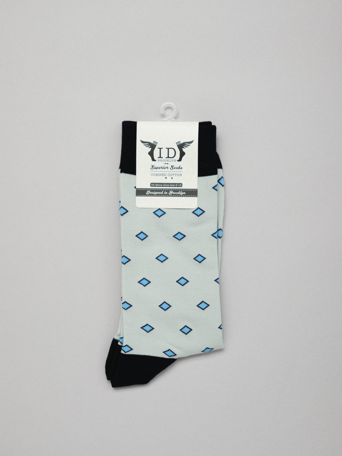 Hishi Graphic Socks by ID Menswear are white with a blue Hishi pattern, featuring black cuffs, toes, and heels. Made from 100% mercerized cotton, they come with a white hanger and IDS label.