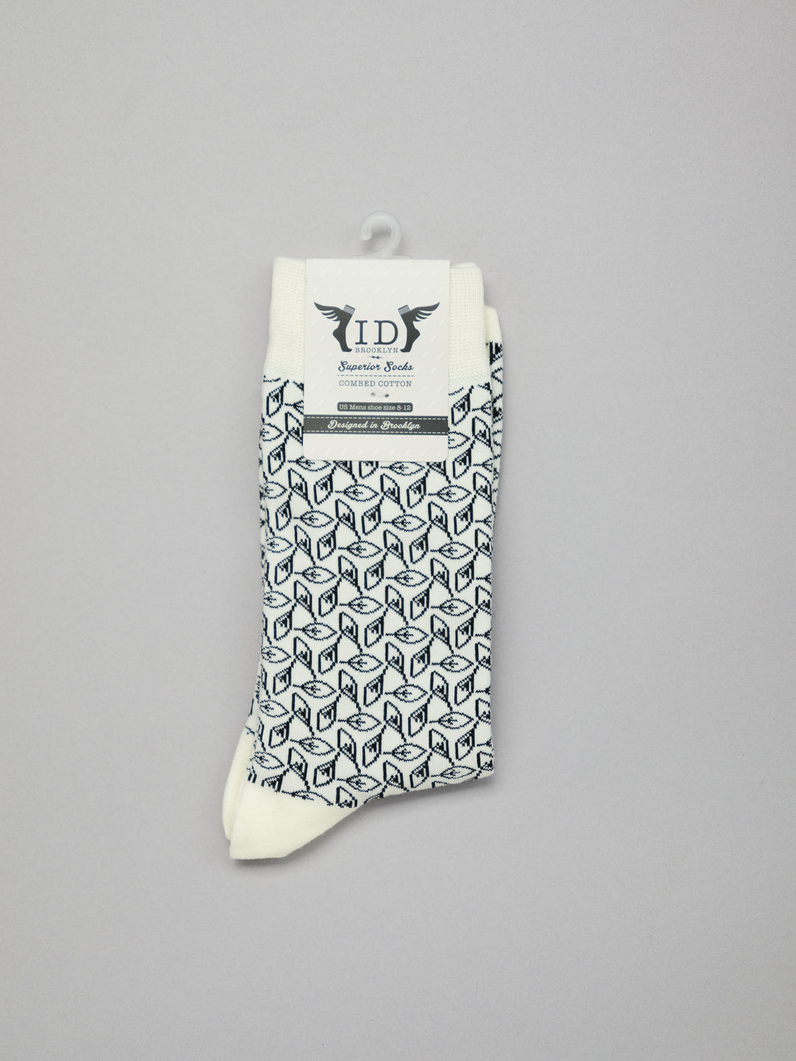 The Fall Graphic Socks from ID Menswear feature a chic white base with a black geometric cube pattern, stretchy and breathable design, and a winged logo label against a sleek gray backdrop.