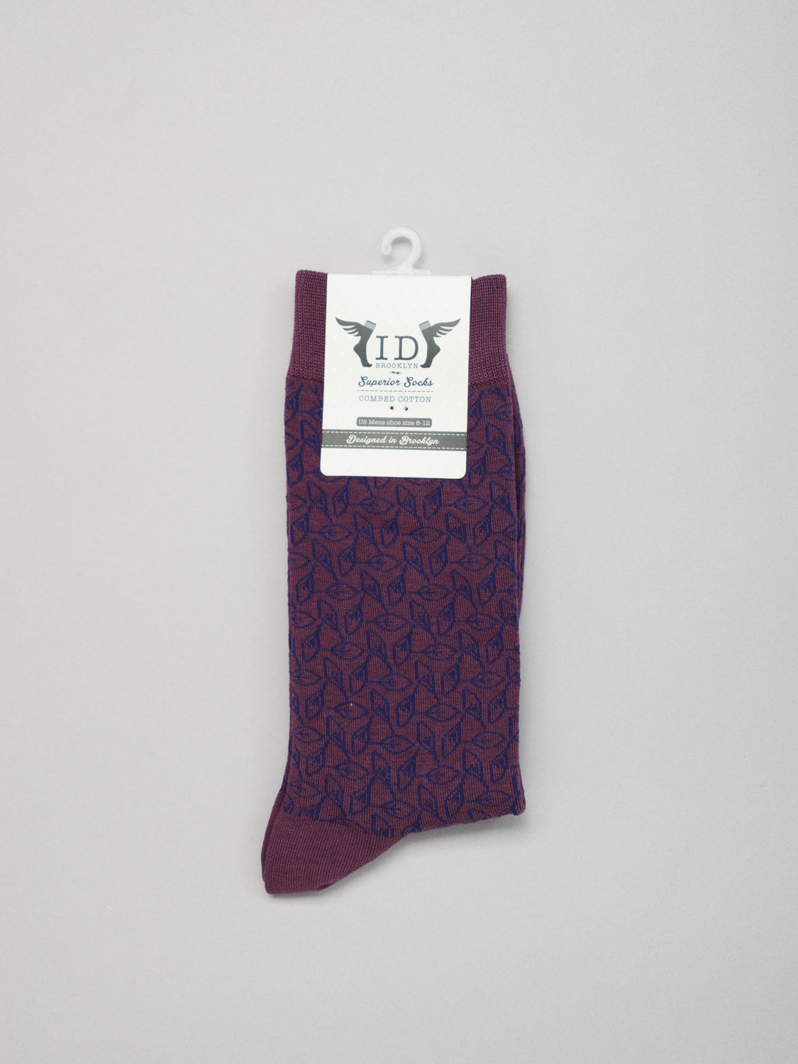The Fall Graphic Socks by ID Menswear feature a purple hue with a subtle geometric pattern. Theyre crafted from soft, stretchy, and breathable combed cotton. These socks showcase a white label near the top with text and logo, making them perfect for crisp fall days.