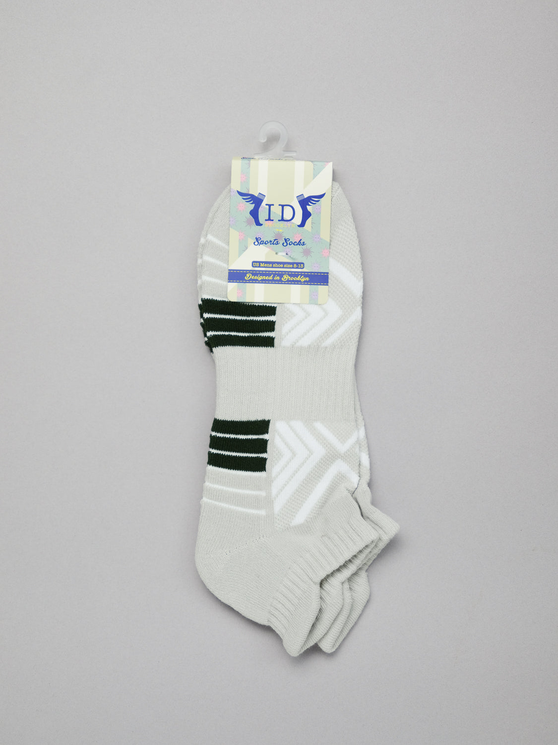 Ankle-length white socks with black and grey stripes are displayed on a light gray background. These breathable, stretchy socks have a label reading YD and Socks with a bird graphic. Product: Ankle Sports Socks by ID Menswear.