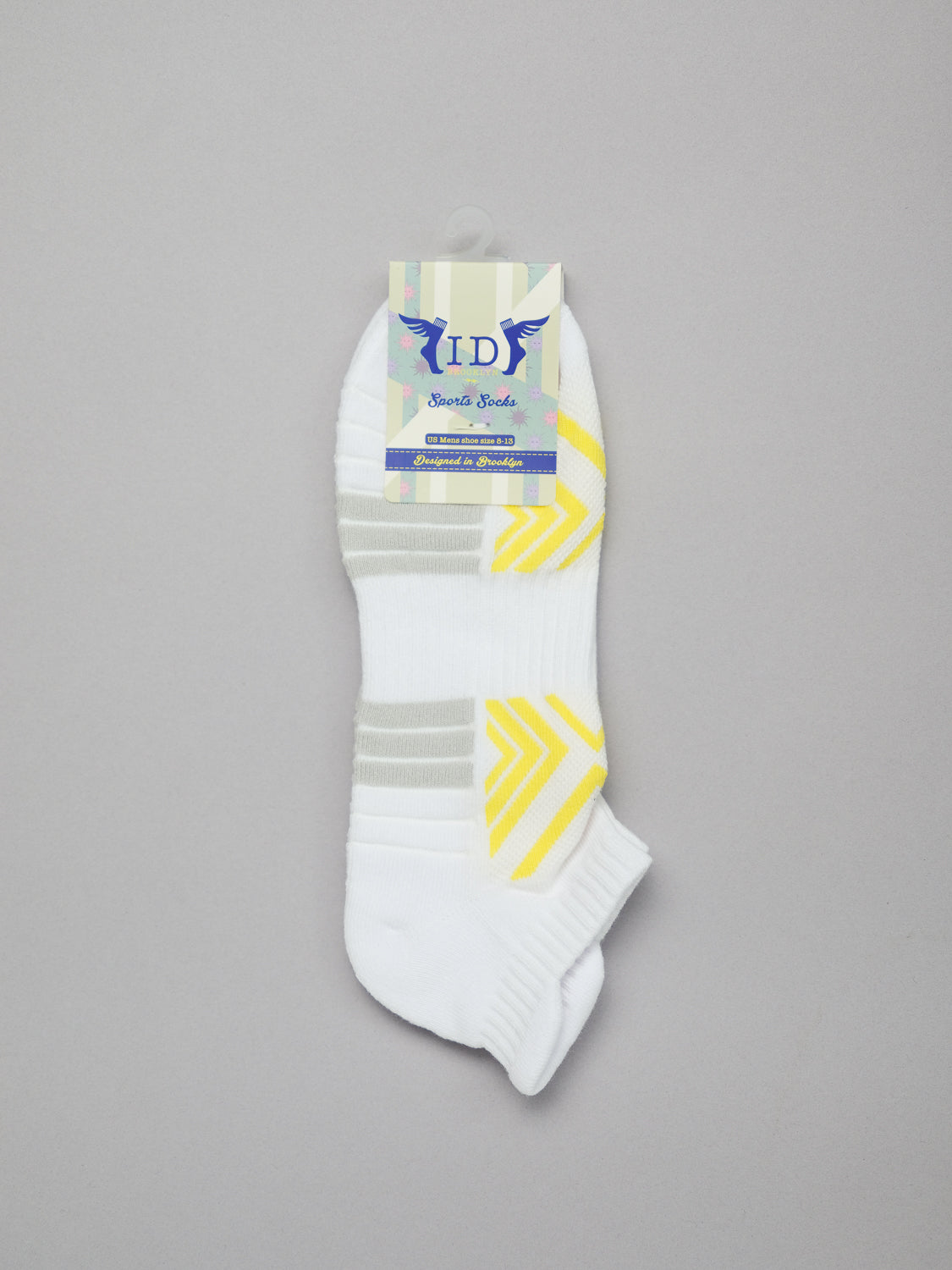 Displayed on a light gray background, ID Menswears Ankle Sports Socks are white with gray and yellow stripes. These breathable, stretchy socks offer extra cushioning for comfort and are attached to a cardboard label at the top.