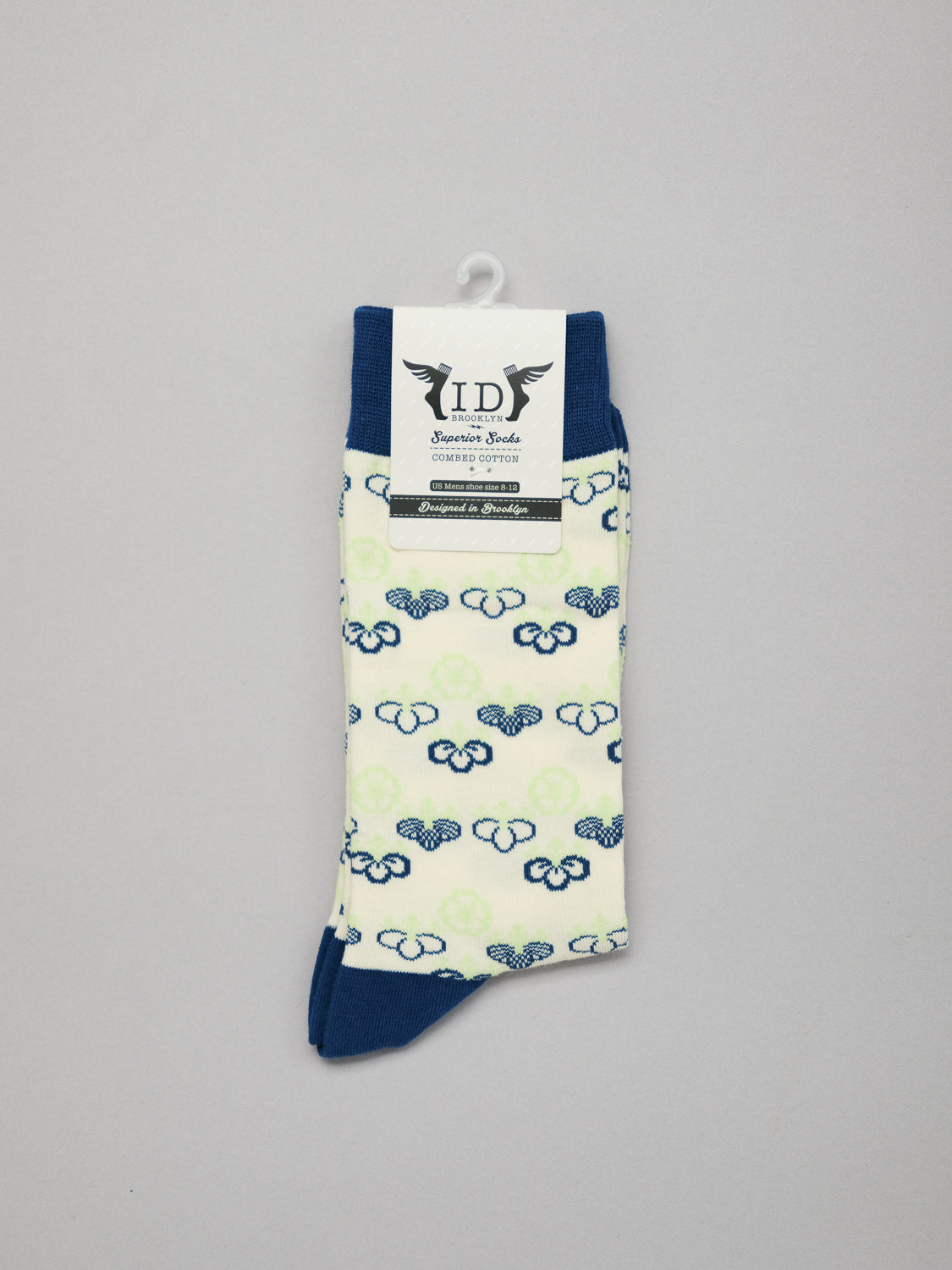The Giri Graphic Socks by ID Menswear are white with a blue heel and toe, showcasing soft, luxurious blue and green cloud patterns inspired by Japanese designs. They are displayed against a plain gray background with a branded label at the top.
