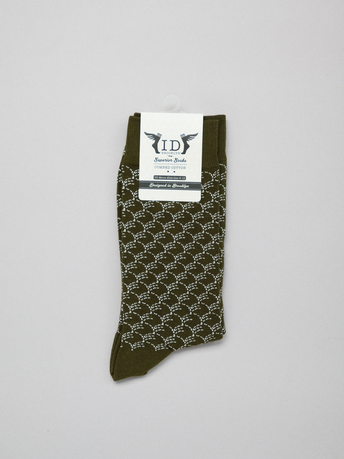 Displayed on a light gray background is a single ID Menswear Broken Waves Graphic Sock, featuring an olive green hue, white geometric pattern, and a top label with a wings logo. Made from combed cotton, it offers breathable and stretchy comfort.
