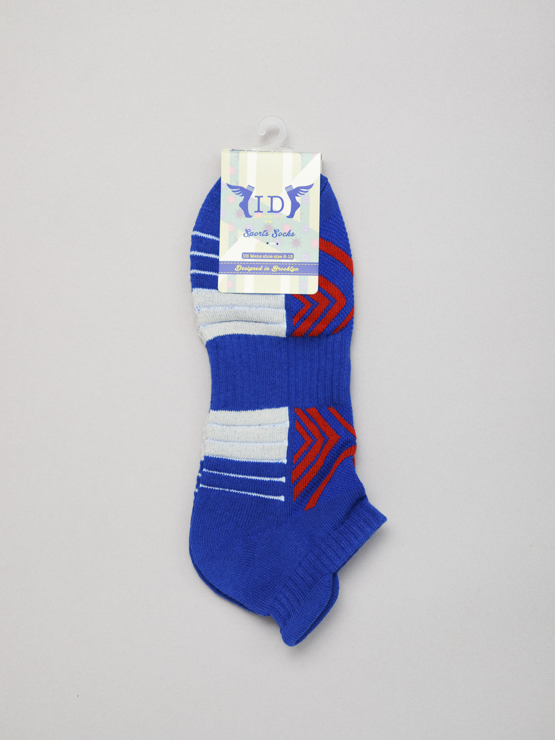 A pair of blue ankle-length Ankle Sports Socks with white and red geometric patterns is displayed against a plain background. The breathable, stretchy socks have a hanging tag labeled ID Menswear.