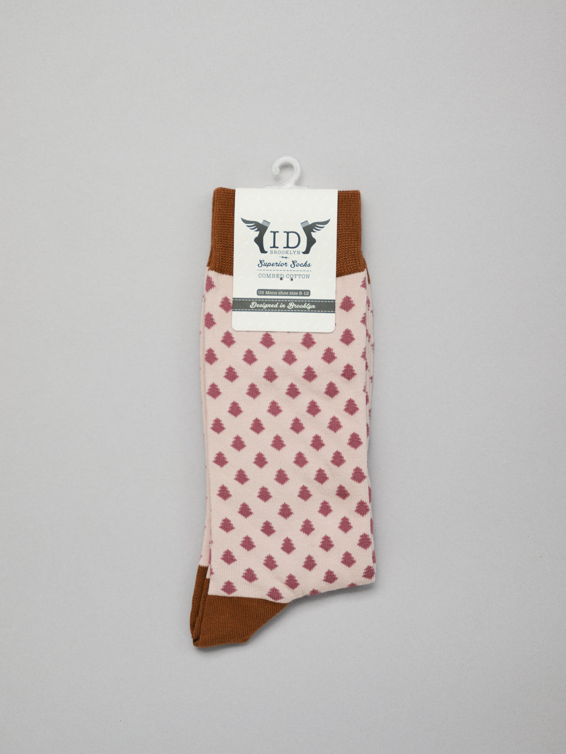A pair of Ogawara Graphic Socks by ID Menswear features a pink and brown diamond pattern reminiscent of Japanese designs, with brown accents on the top and toe. Its packaged with a white hook tag labeled ID in cursive, along with additional text and design elements.