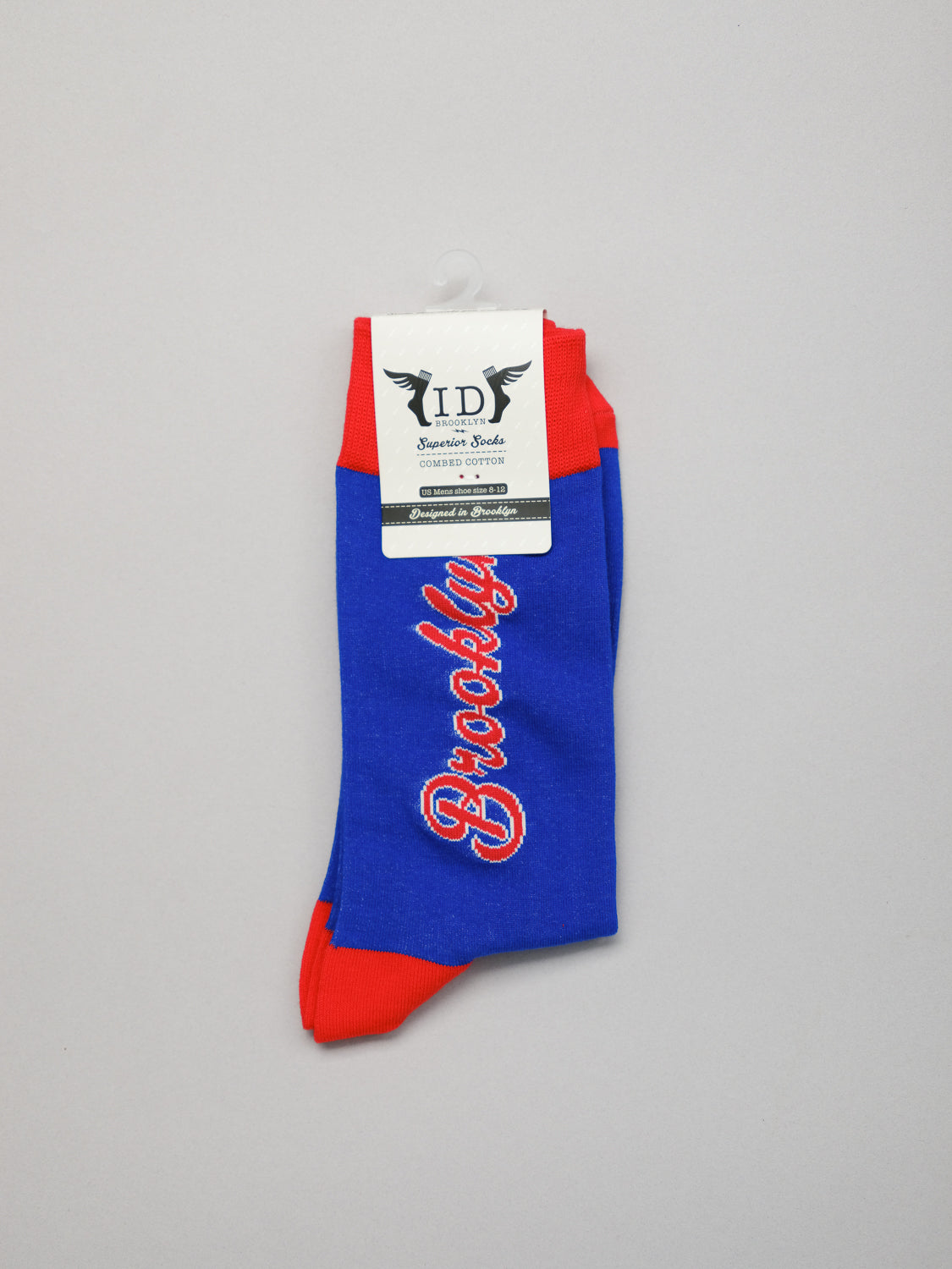 The Brooklyn Graphic Socks from ID Menswear, in blue and red, crafted from premium combed cotton, feature Brooklyn embroidered in white and red. Theyre neatly folded with a tag showcasing a winged logo.
