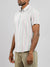 A man wears the Streak Cotton Shirt by ID Menswear, a regular fit lightweight cotton shirt featuring short sleeves and pastel vertical stripes of pink, green, and blue. He pairs it with light olive pants against a plain gray background.