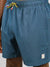 Close-up of a person in ID Menswears Uroko Fast Dry 4-Way Stretch Swim Trunk, featuring blue and green geometric patterns, yellow-black drawstring, small rectangular patch near the hem, and quick-dry fabric for all-day comfort.