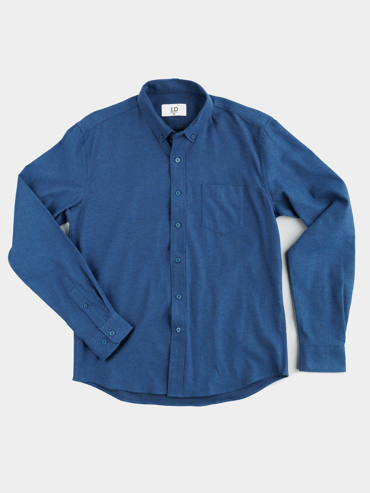 A Magnus Brushed Twill Solid Flannel Shirt by ID Menswear, featuring long sleeves, button-down collar, buttoned cuffs, and a chest pocket in blue, is laid flat against a light background.
