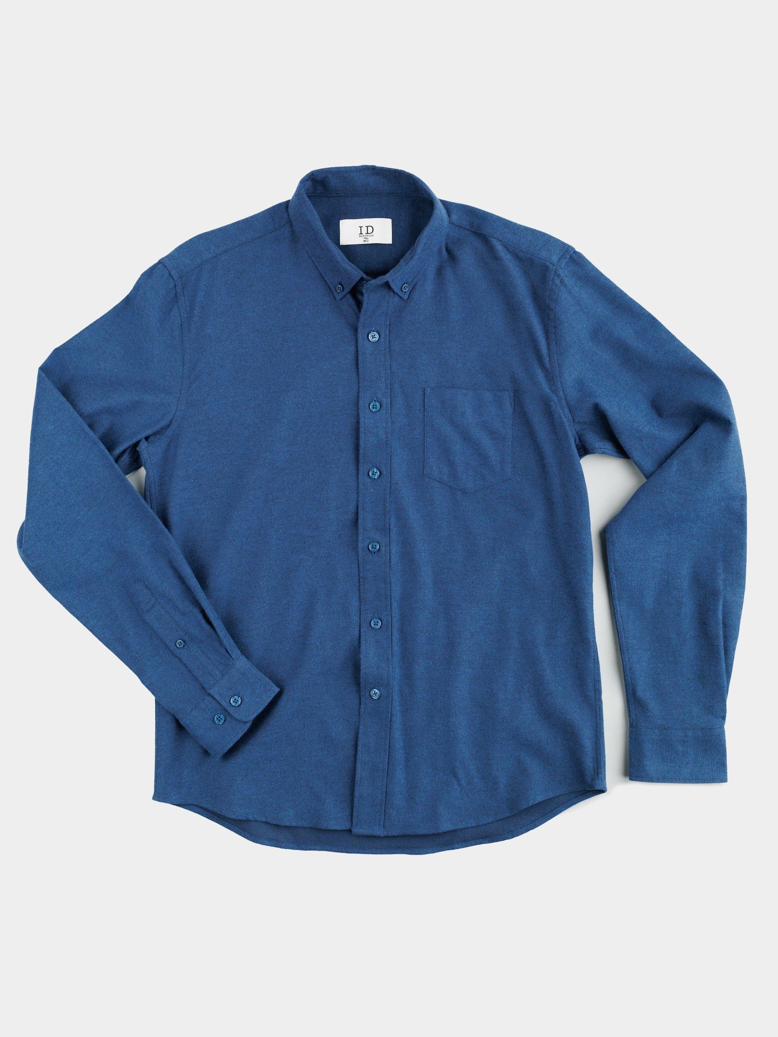 A Magnus Brushed Twill Solid Flannel Shirt by ID Menswear, featuring long sleeves, button-down collar, buttoned cuffs, and a chest pocket in blue, is laid flat against a light background.