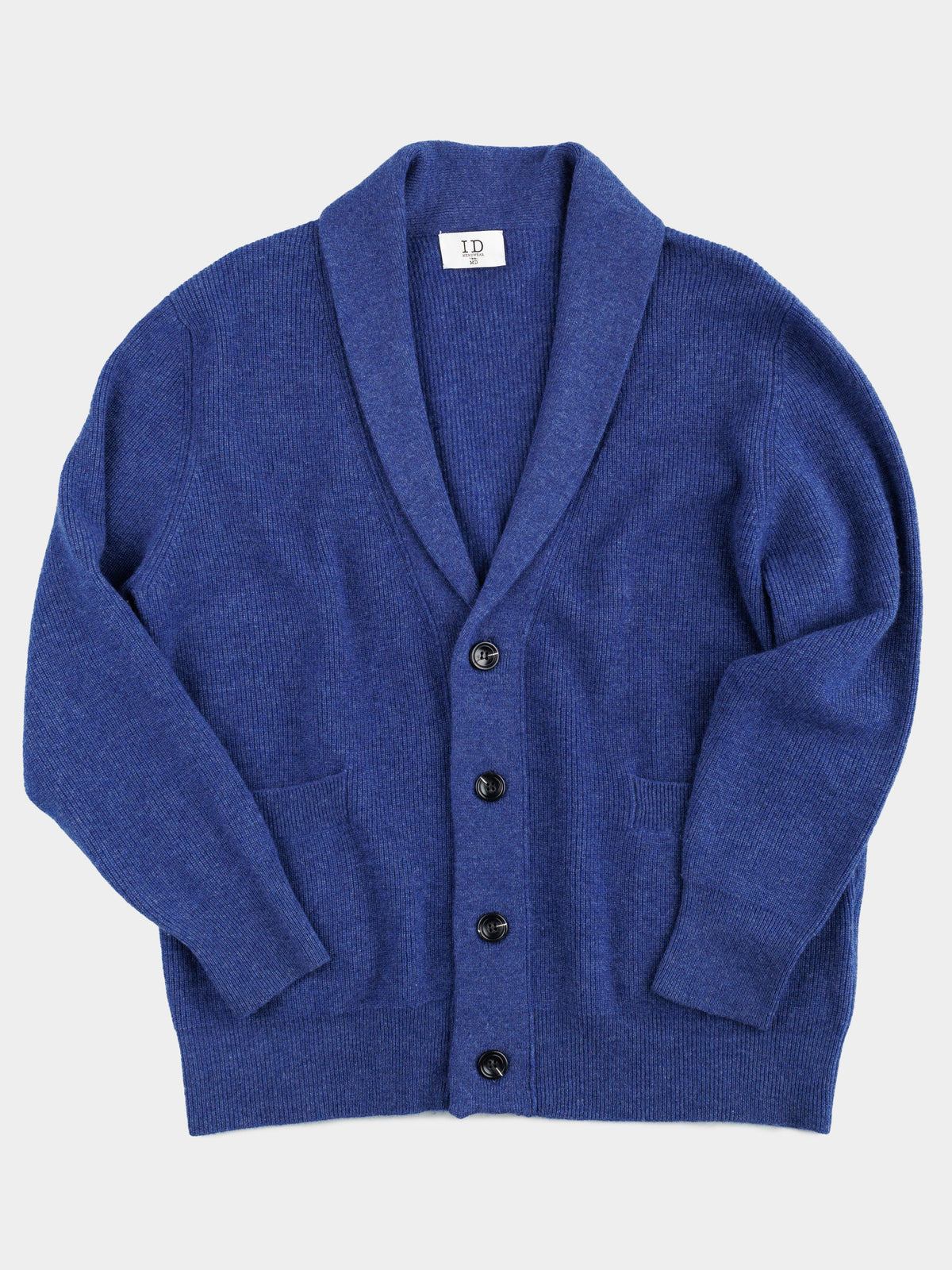 The Basecamp Cashmere Merino Cardigan from ID Menswear is a winter wardrobe essential, featuring a blue shawl collar, five black buttons, ribbed knit fabric, long sleeves, and two front pockets. Crafted from a luxurious cashmere merino blend, it perfectly combines style and comfort.