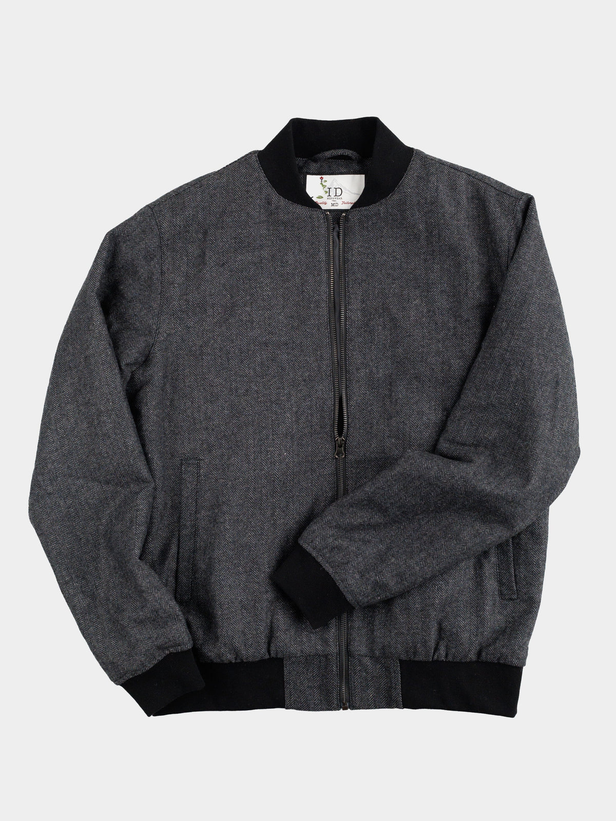 The Montauk Wool Blend Jacket by ID Menswear, crafted from gray tweed, offers lightweight comfort with black cuffs, collar, and waistband. On a white background, it shows the front view with a visible black zipper and two side pockets.