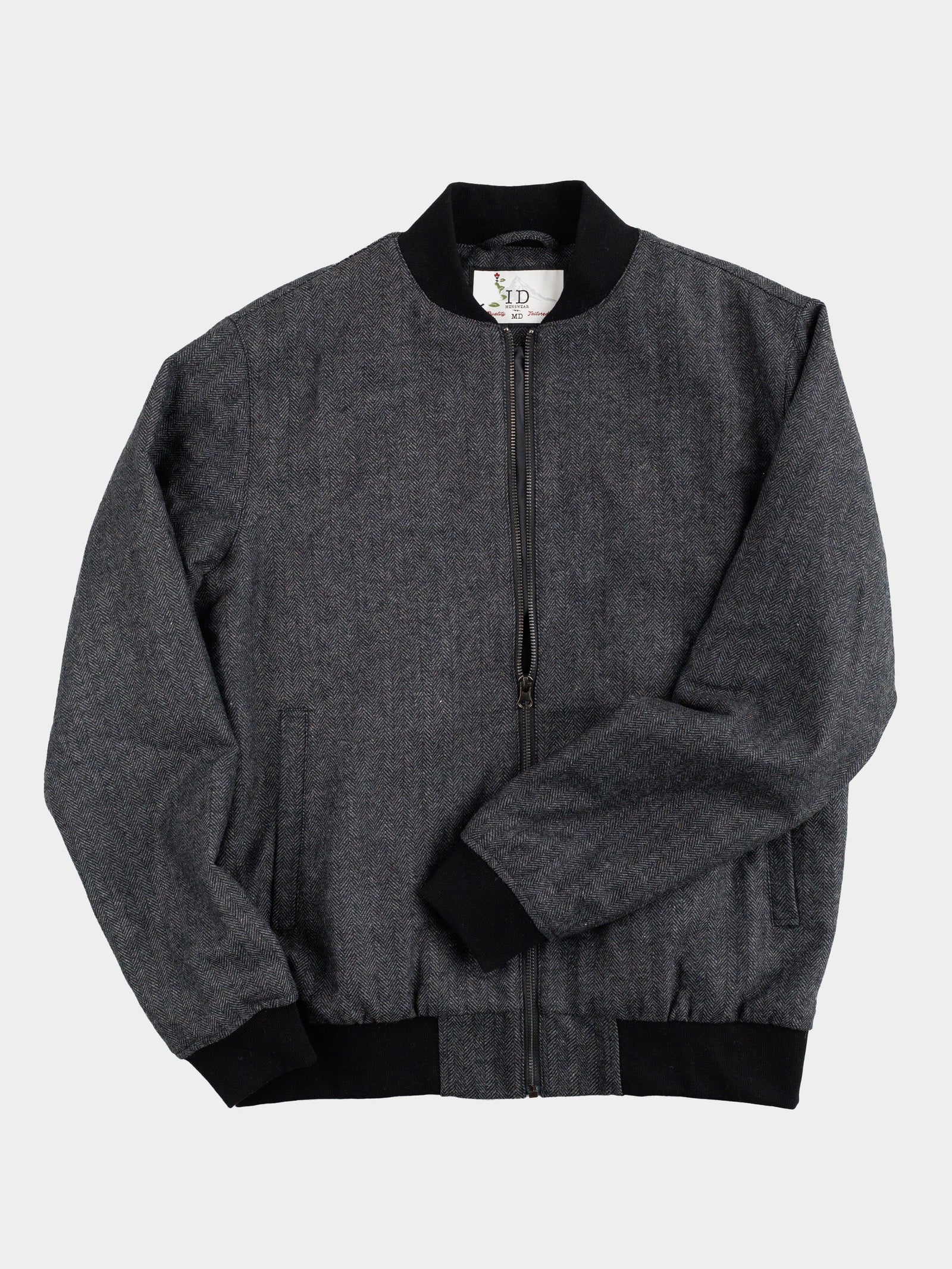 The Montauk Wool Blend Jacket by ID Menswear, crafted from gray tweed, offers lightweight comfort with black cuffs, collar, and waistband. On a white background, it shows the front view with a visible black zipper and two side pockets.