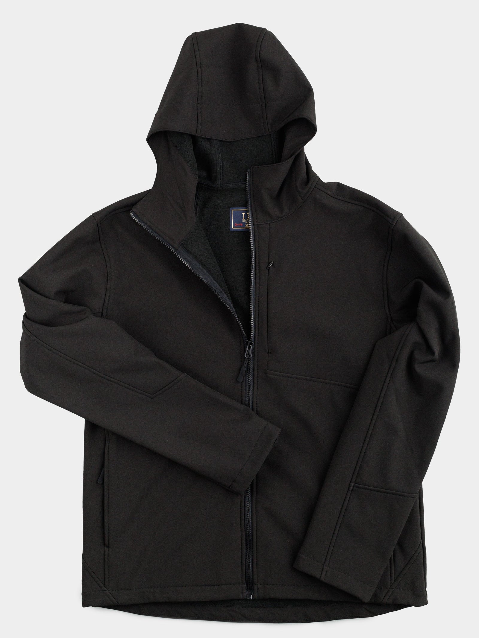 The Fairbanks Soft Shell Hooded Jacket by ID Menswear is a black, lightweight jacket with a front zipper, two front pockets, and an extra chest pocket. It’s shown on a white background and features smooth material with an upright hood; one sleeve is partly folded over the torso.