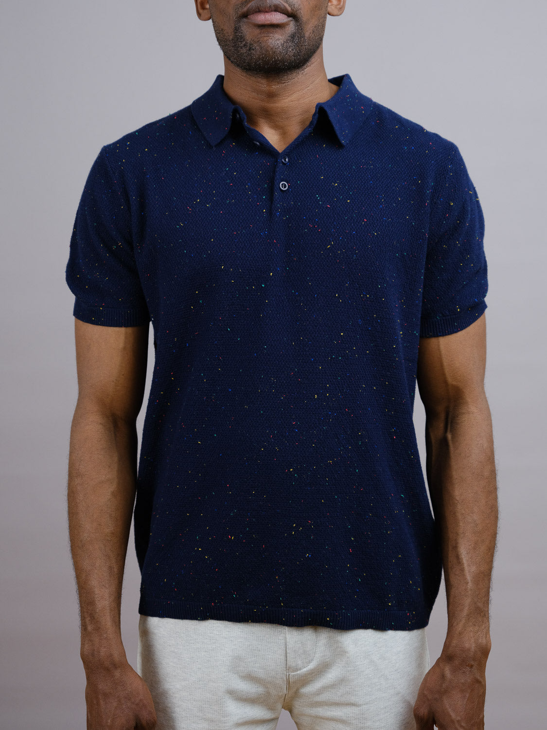 A man, face partially out of frame, stands against a plain background in the New Austin Knitted Cotton Polo by ID Menswear—ideal for casual wear—paired with light-colored pants.