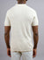 A person, back to the camera, wears a short-sleeved cream New Austin Knitted Cotton Polo by ID Menswear and light pants—an easy casual choice—against a plain gray background.