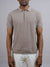 A man models the Tucson Knitted Cotton Polo by ID Menswear in textured light brown with light pants, standing against a plain gray background. His face is partially out of frame, highlighting this versatile casual piece.
