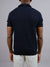 A person is seen from the back wearing ID Menswear’s Agra Knitted Cotton Polo in dark blue with light pants, set against a plain gray background for a comfortable, casual look.