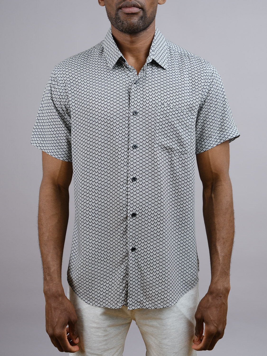 A man wears the Toyo Japanese Print Shirt by ID Menswear, a lightweight short-sleeve rayon shirt with a small black and white geometric pattern, standing against a plain gray background.
